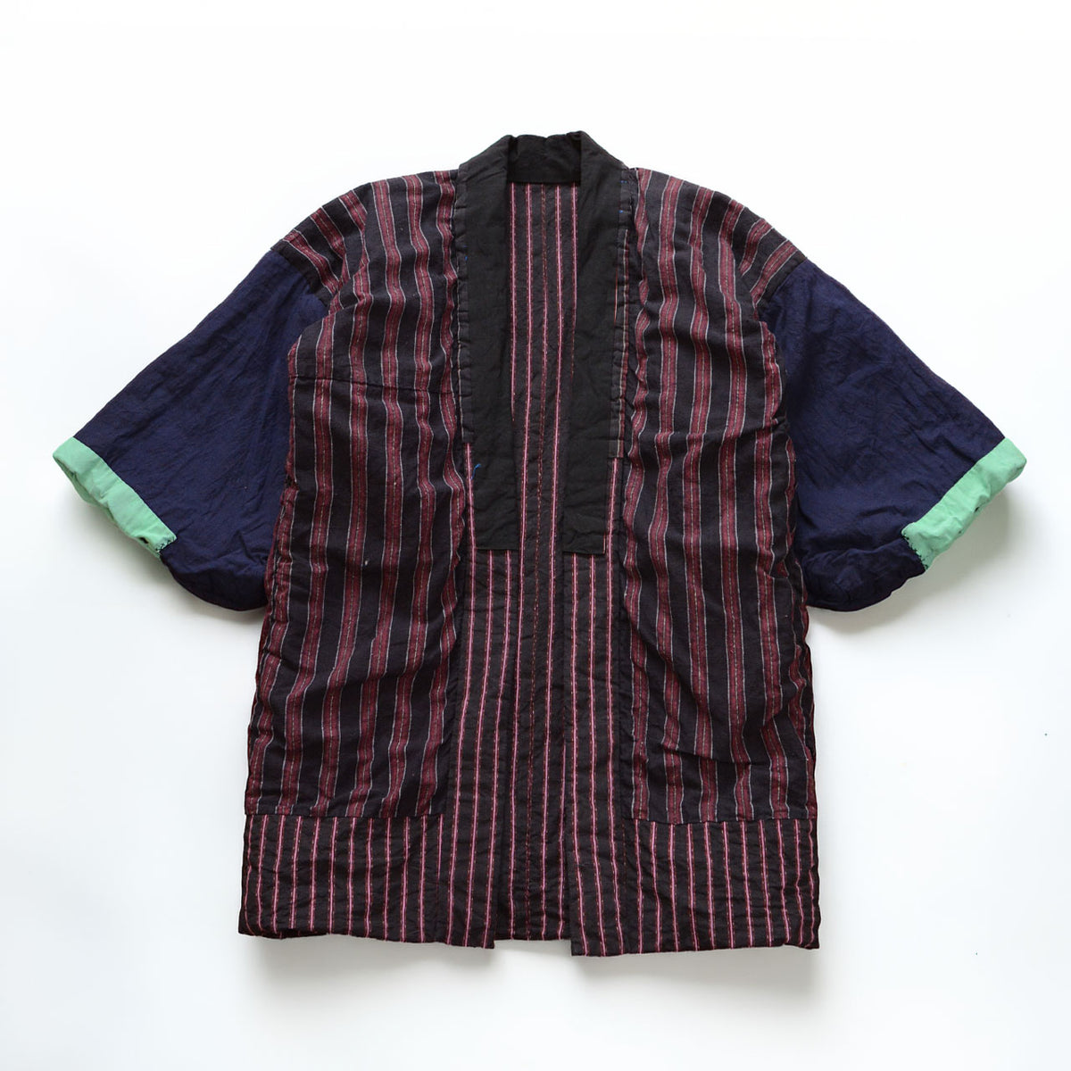 Japanese vintage cotton noragi showing the reverse side laid flat, with a striped body, solid navy sleeves, mint-green cuffs, and a crazy-pattern lining