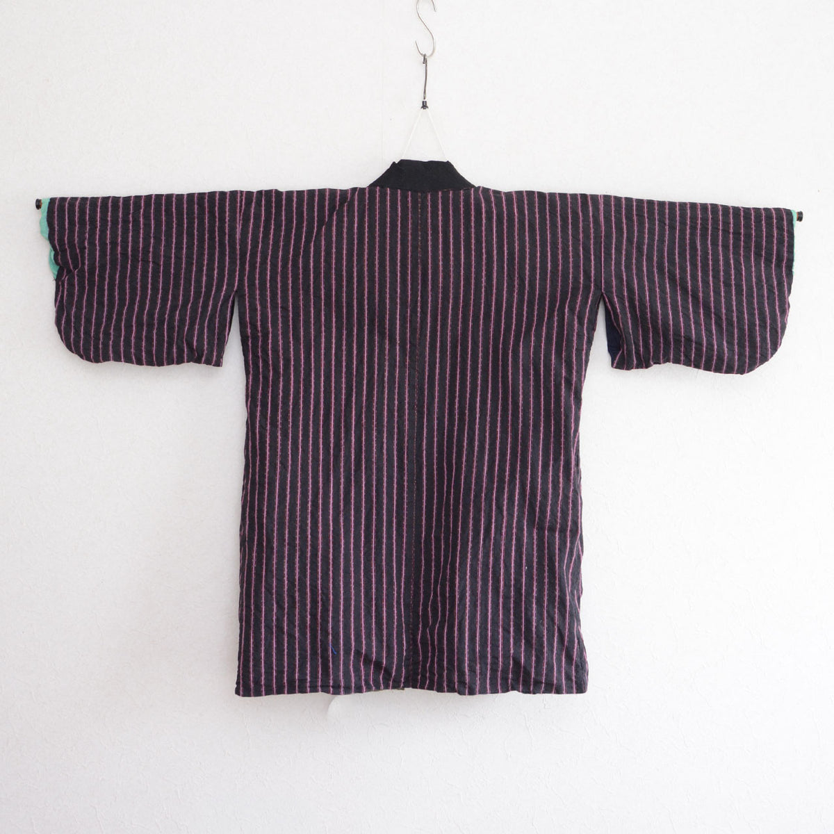 Japanese vintage cotton noragi on a kimono hanger, showing the striped body, black collar facing, and reverse-side construction