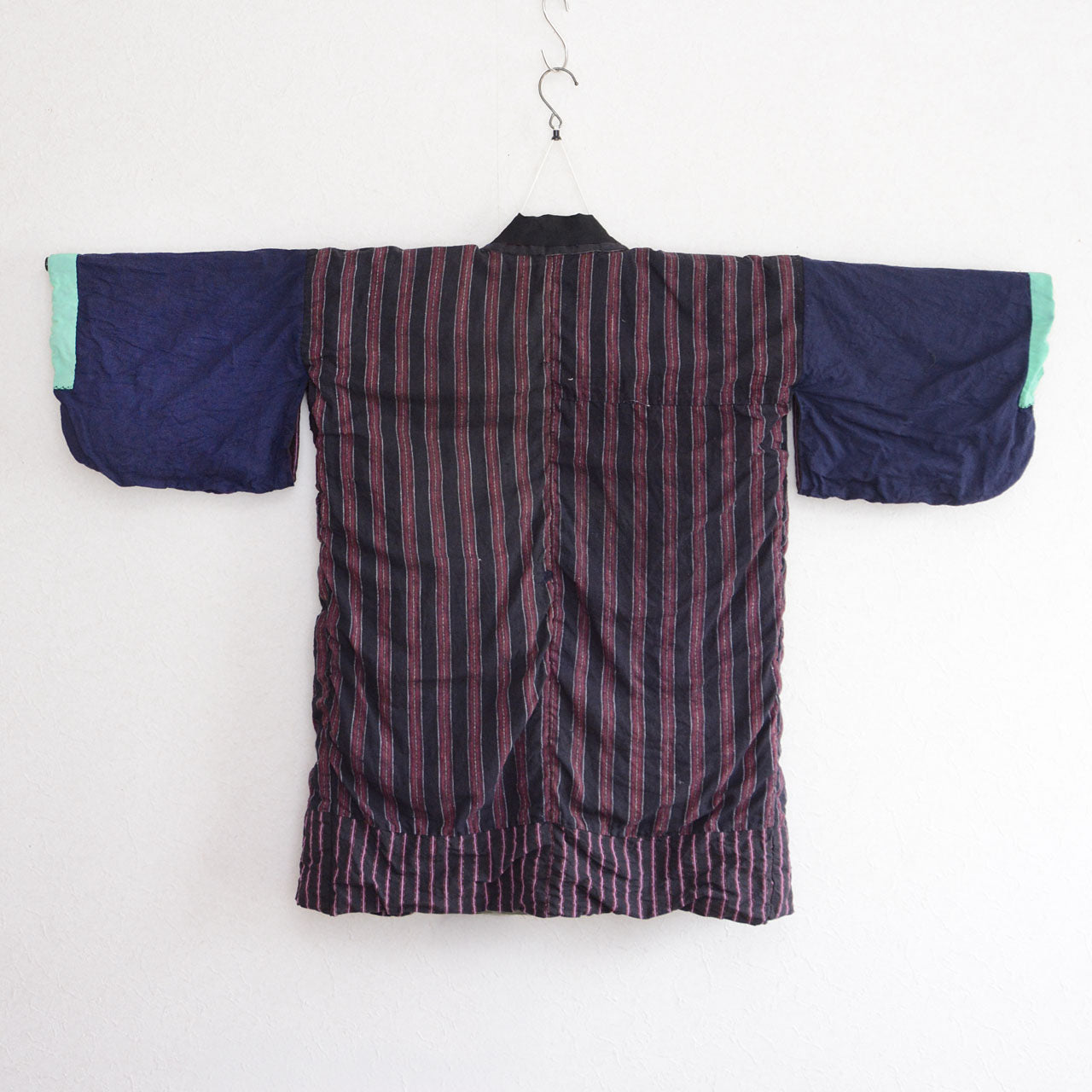 Japanese vintage cotton noragi on a kimono hanger, with a dark striped body, navy sleeves, mint-green cuffs, and black collar