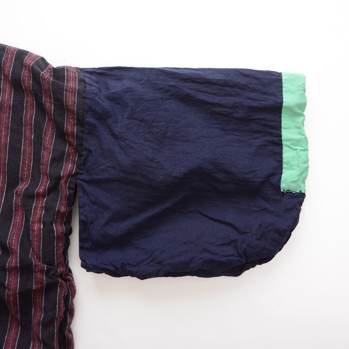 Detail of a Japanese vintage noragi showing the solid navy sleeve, mint-green cuff, and transition to the striped body