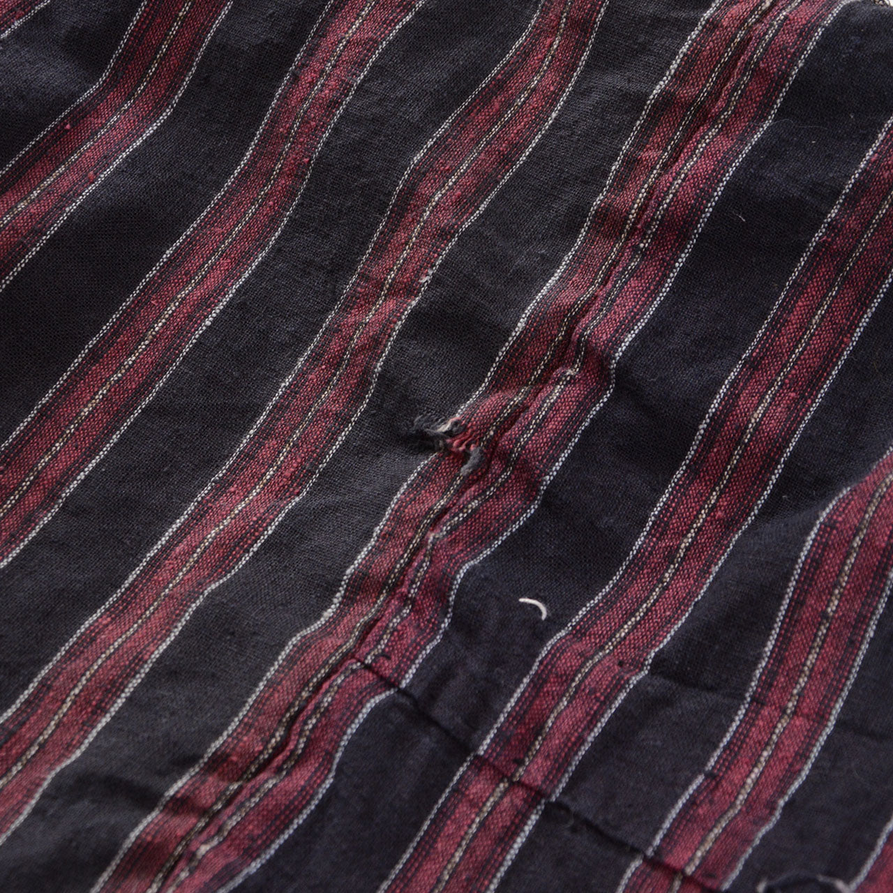 Detail of a Japanese vintage noragi showing red, white, and pink vertical stripes with central damage