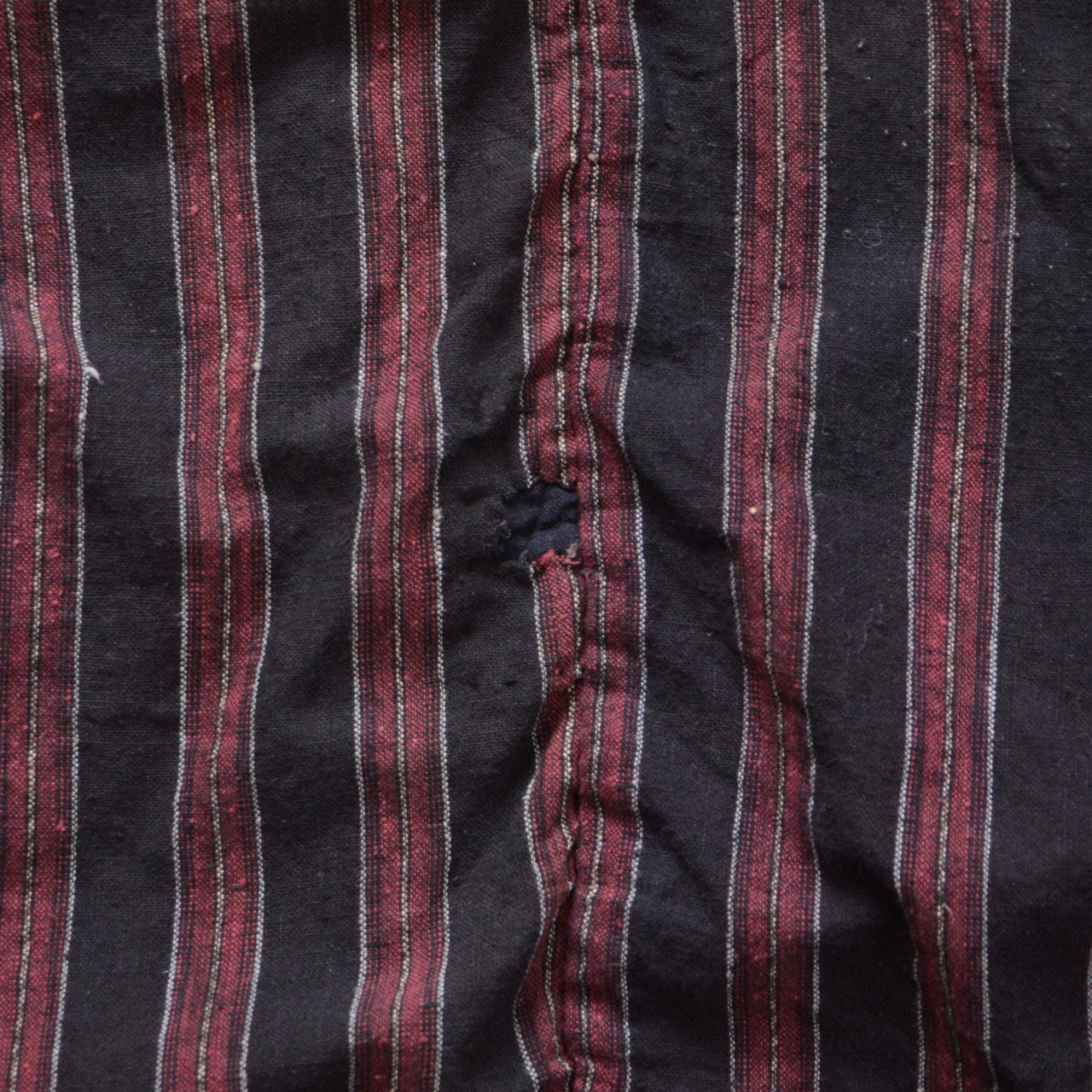 Repair work on the striped cotton fabric of a Japanese vintage noragi