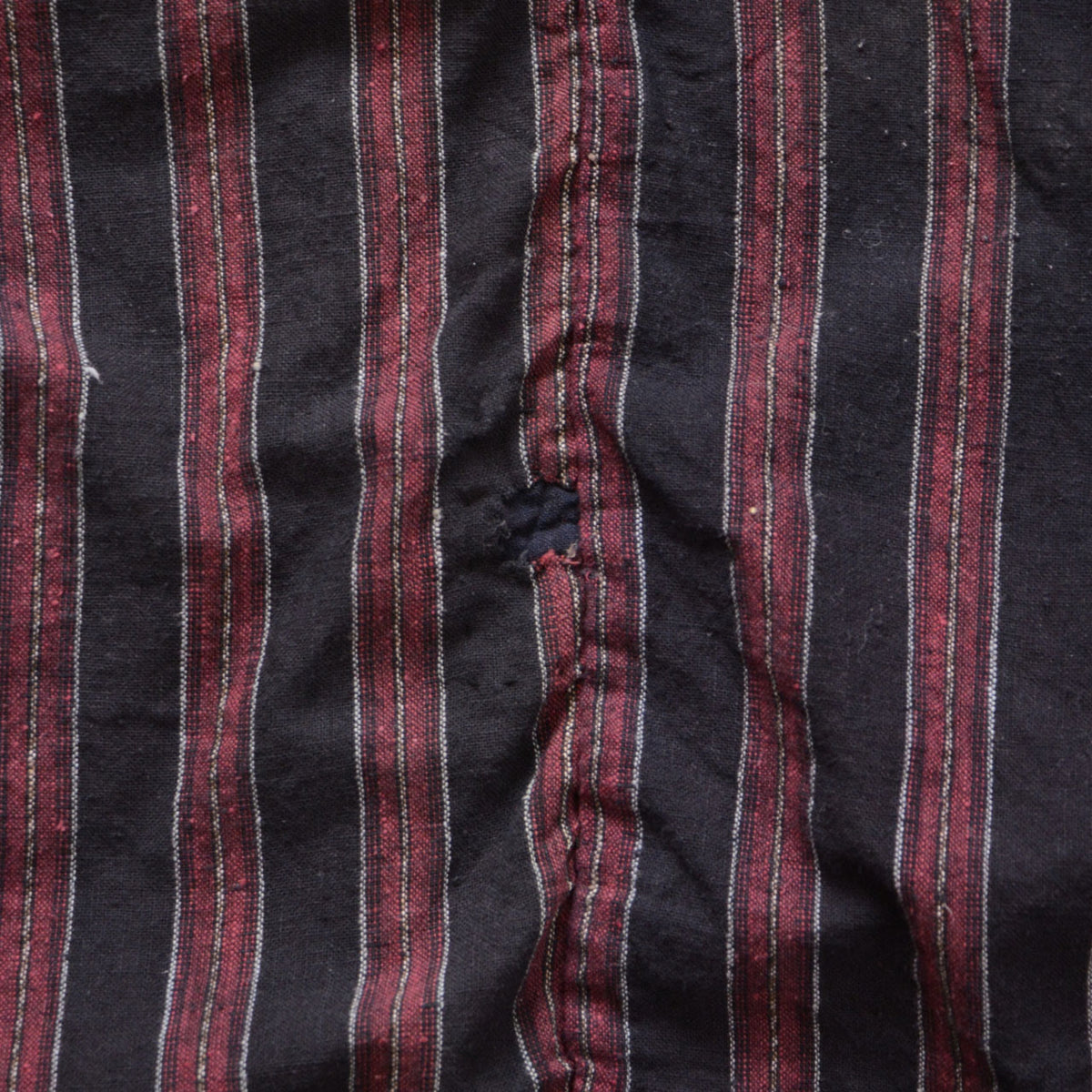 Repair work on the striped cotton fabric of a Japanese vintage noragi