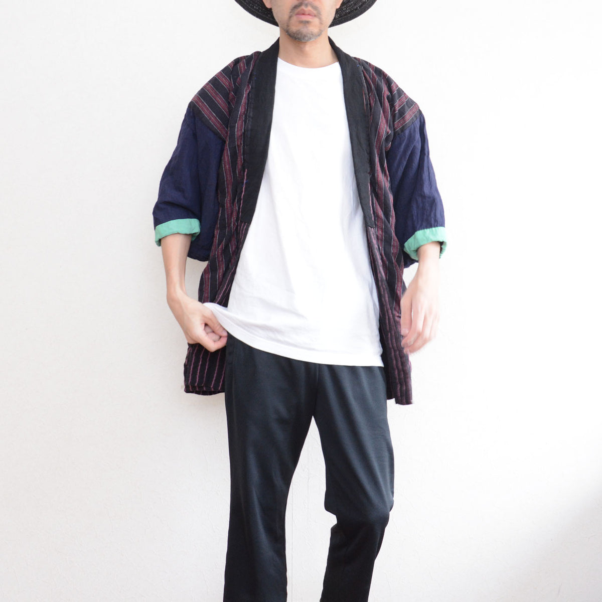 Model wearing a Japanese vintage cotton noragi with a striped body, navy sleeves, mint-green cuffs, and track pants