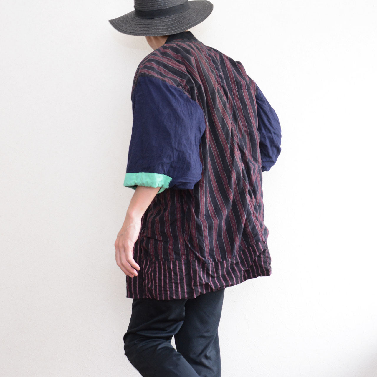 Front of a model wearing a Japanese vintage cotton noragi with a striped body, contrasting navy sleeves, mint-green cuffs, and track pants