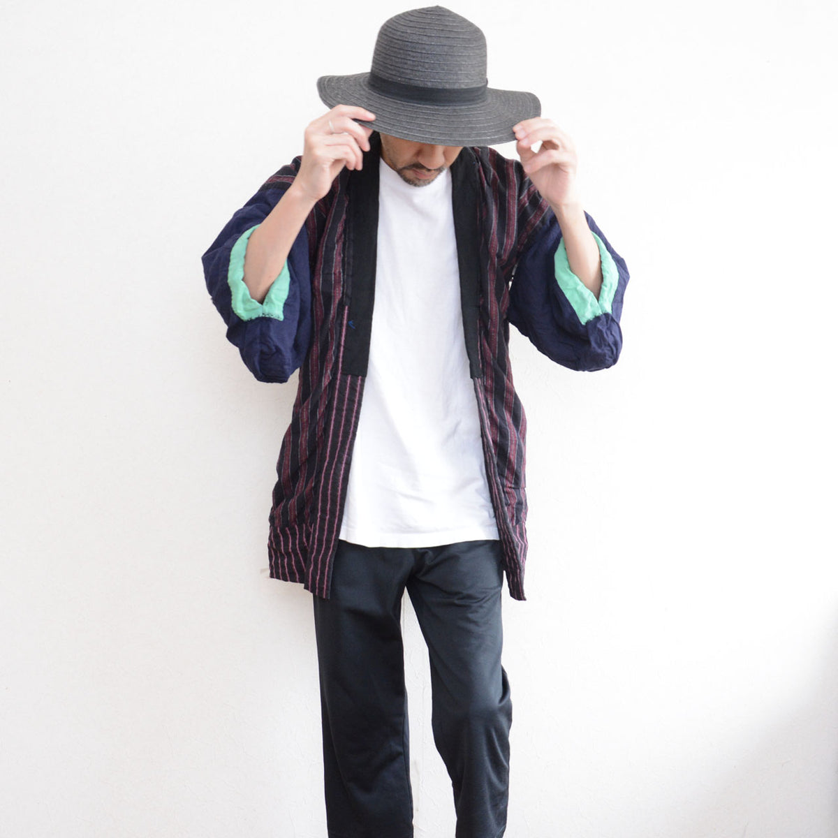Model wearing a Japanese vintage noragi with striped cotton panels, navy sleeves, mint-green cuffs, and track pants