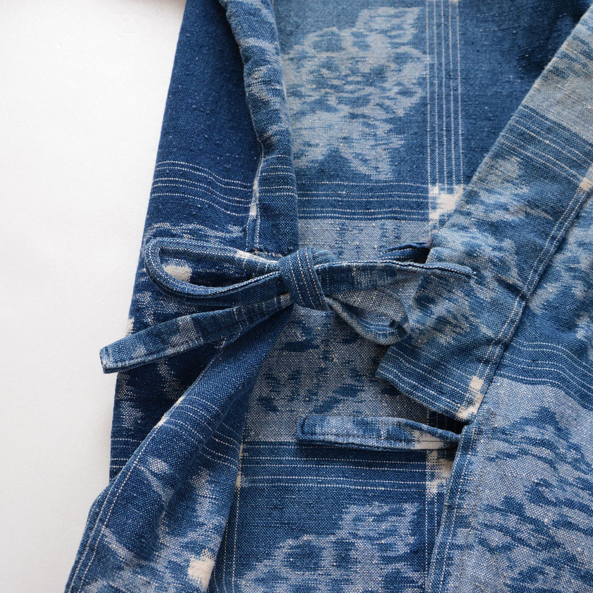 Patterned cotton fastening ties on an indigo uwappari noragi jacket with botanical grid motifs