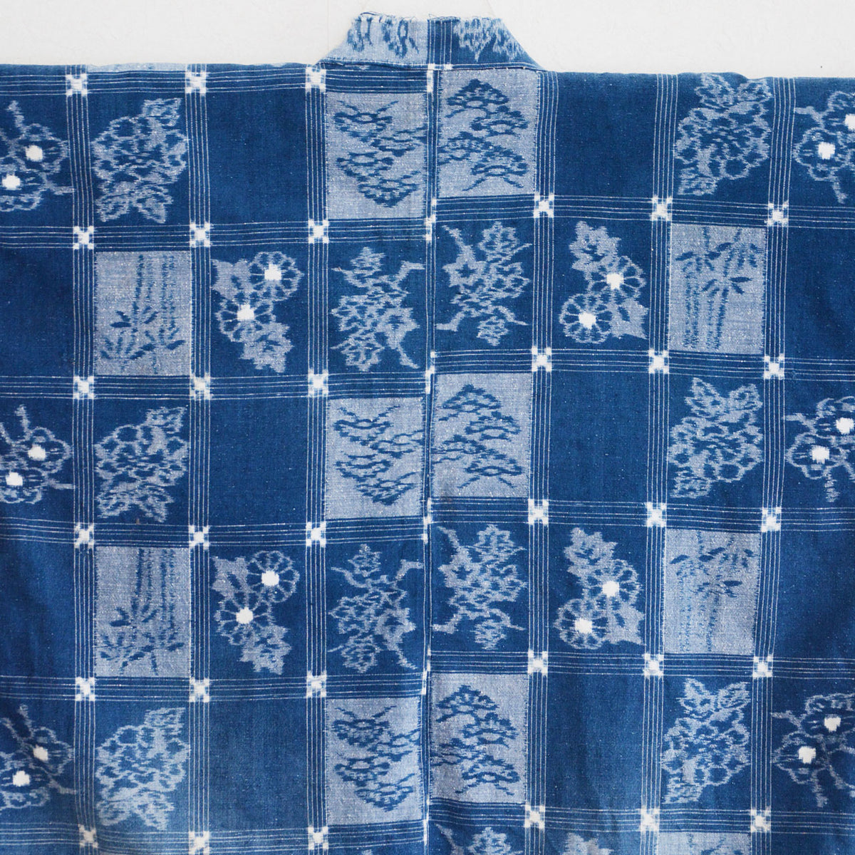 Indigo cotton noragi fabric with fine grid lines, floral motifs and pine-like and bamboo-like botanical motifs
