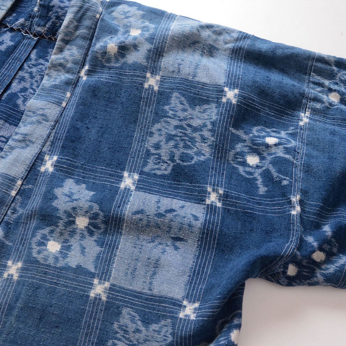 Indigo cotton uwappari noragi fabric with alternating blue tones, fine grid lines and floral and botanical motifs