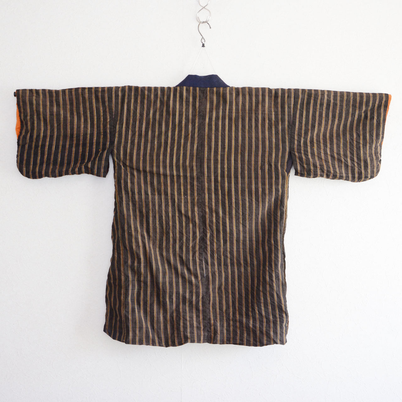 Vintage Japanese noragi jacket, Showa era, dark brown and navy vertical stripe outer fabric, back view, wide kimono-style sleeves with orange cuff detail