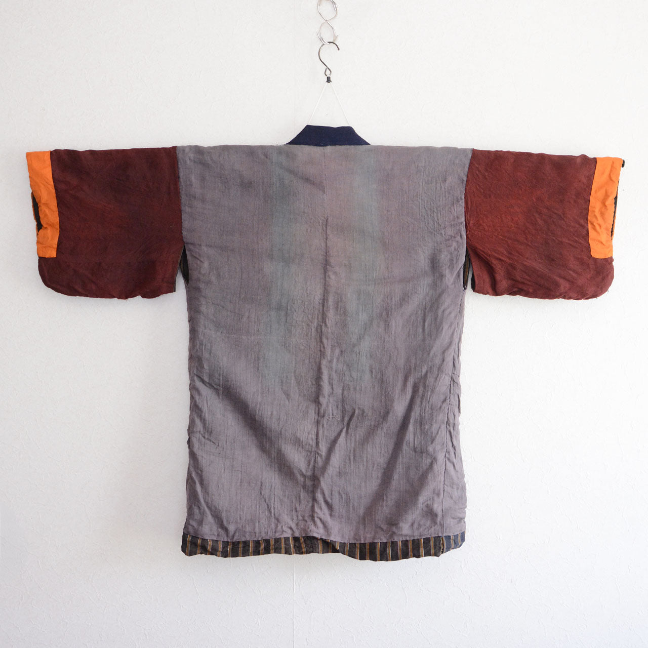 Vintage Japanese noragi jacket, Showa era, gray mixed fabric, back view, burgundy and orange patchwork sleeves, dark vertical stripe hem lining detail