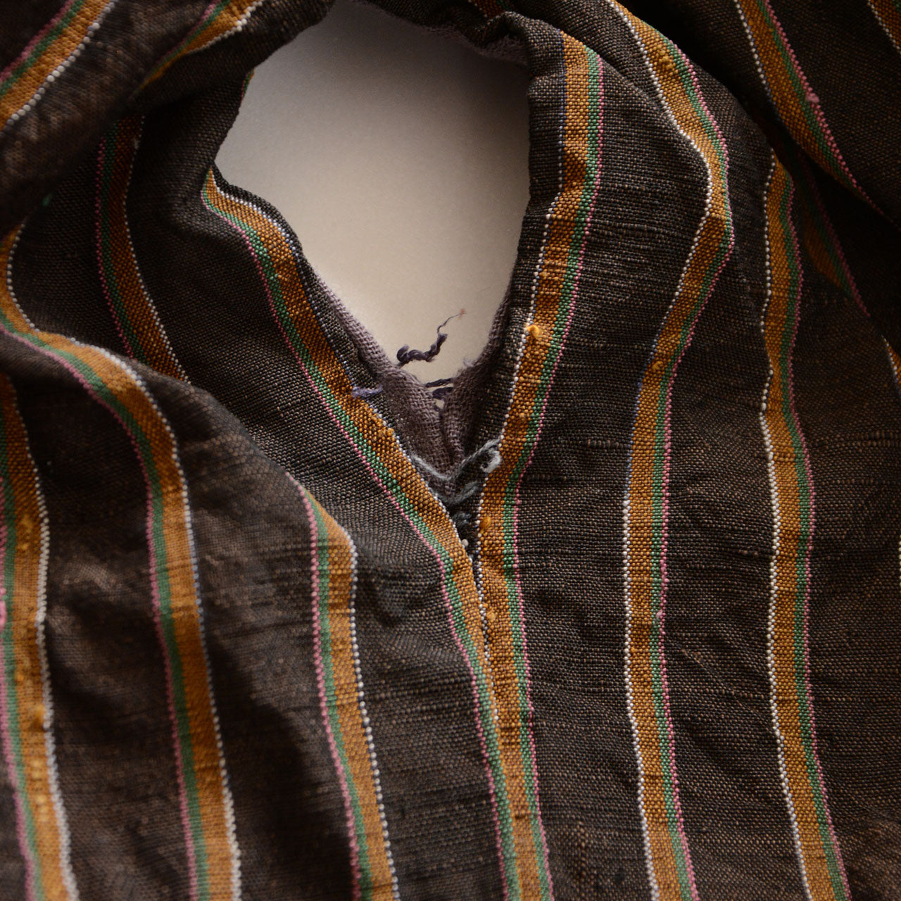 Vintage Japanese noragi jacket, Showa era, dark ground multicolor stripe fabric with ochre, green, pink, and white thread stripes, front collar opening detail with loose thread