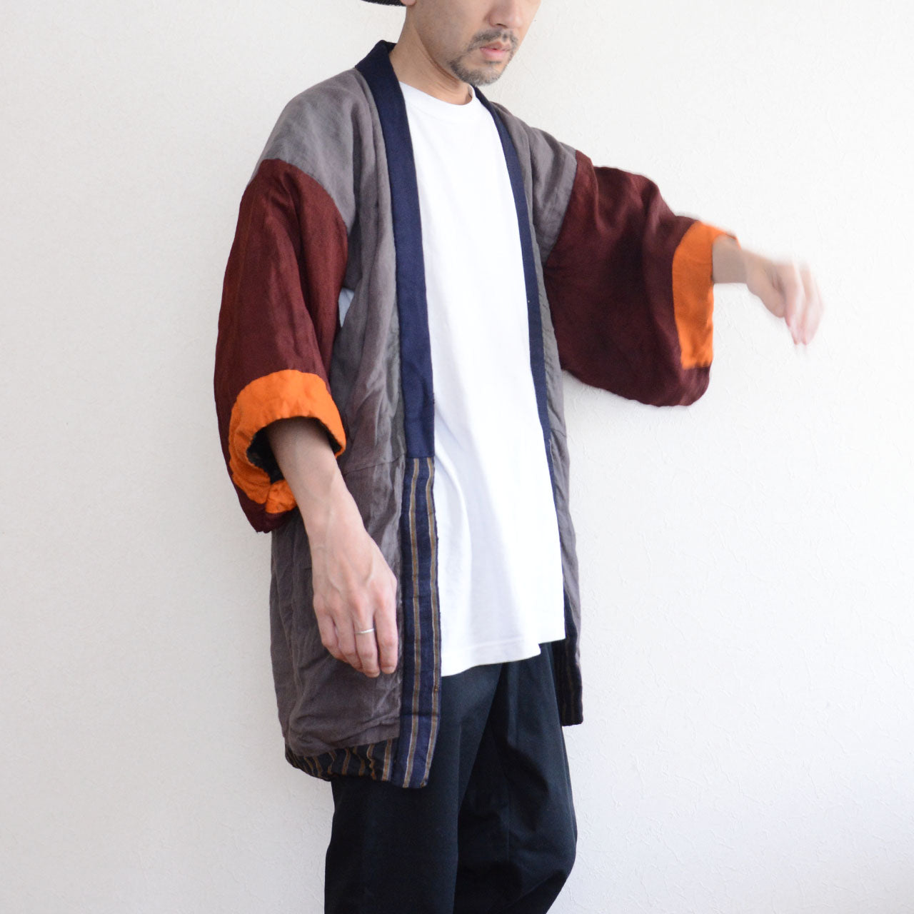 Vintage Japanese noragi jacket, Showa era, gray mixed fabric body with burgundy and orange patchwork sleeves, worn open over white t-shirt and dark trousers, front side view, model height 171cm