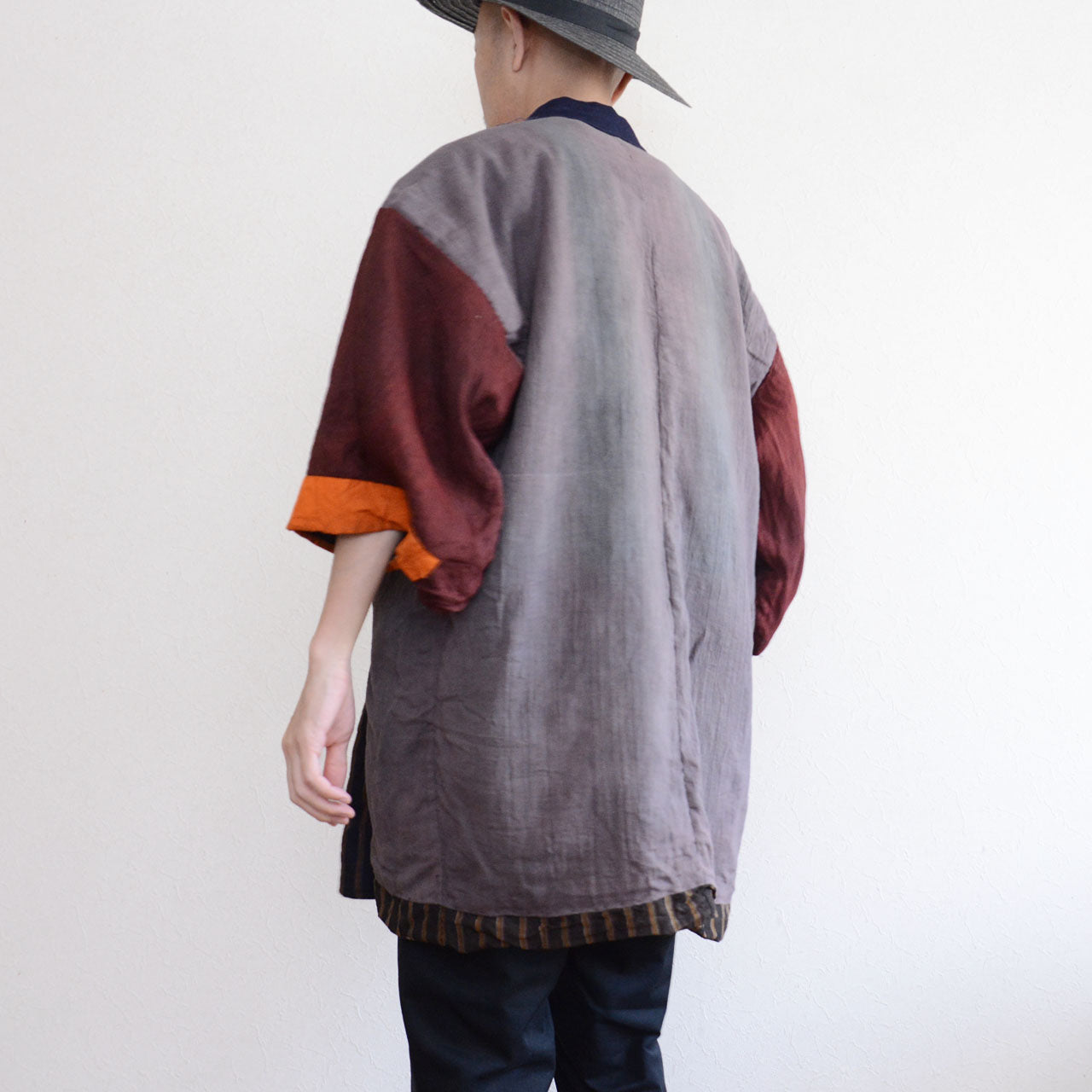 Vintage Japanese noragi jacket, Showa era, gray mixed fabric body with burgundy and orange patchwork sleeves, multicolor stripe lining visible at hem, back view, model height 171cm