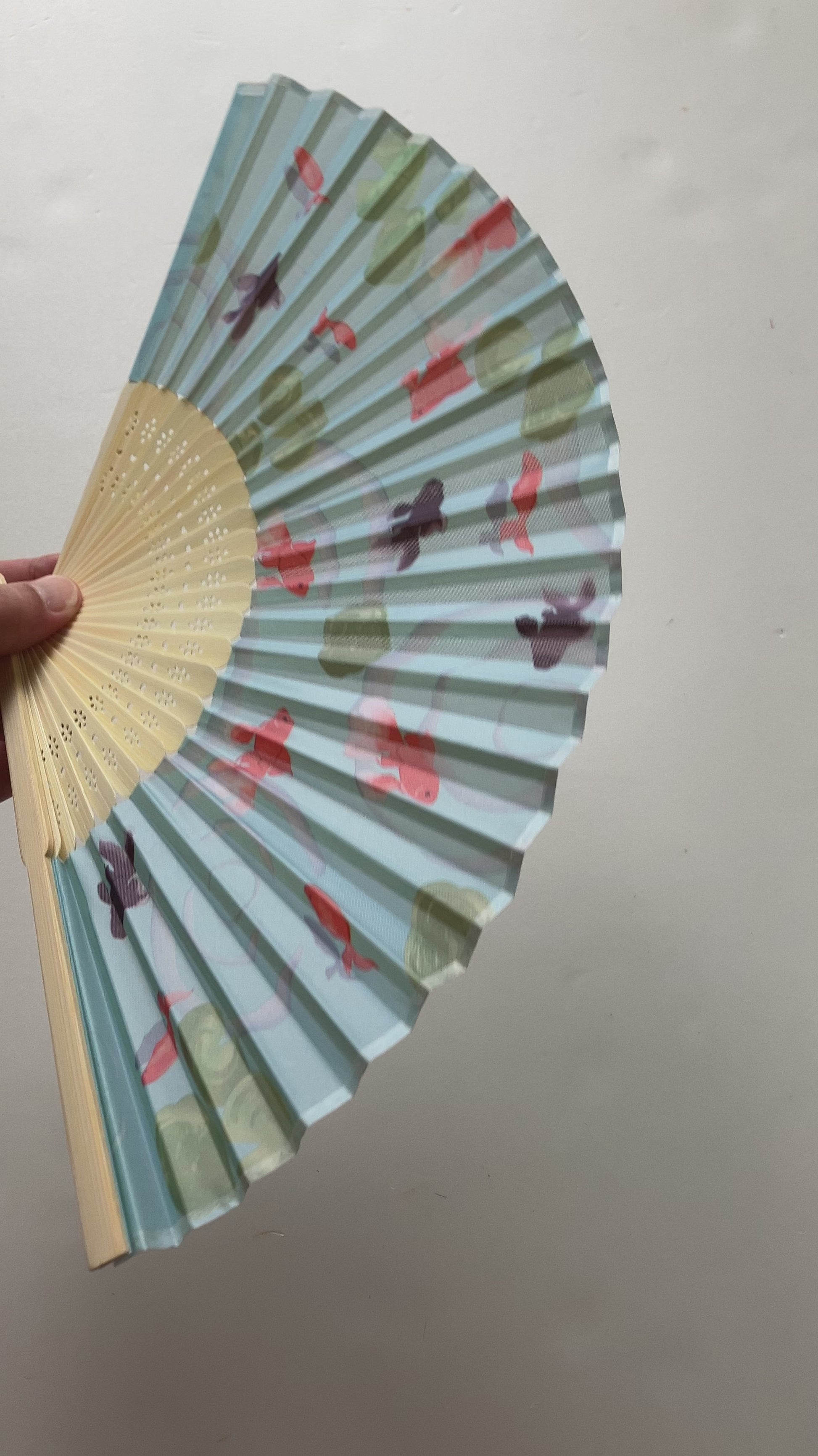 Japanese folding fan gently fanned open showcasing goldfish and demekin design