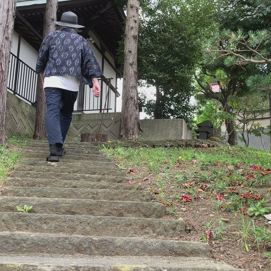Faded black kasuri noragi worn while climbing stone steps of a Japanese shrine, mid-Showa era Japan vintage slow fashion