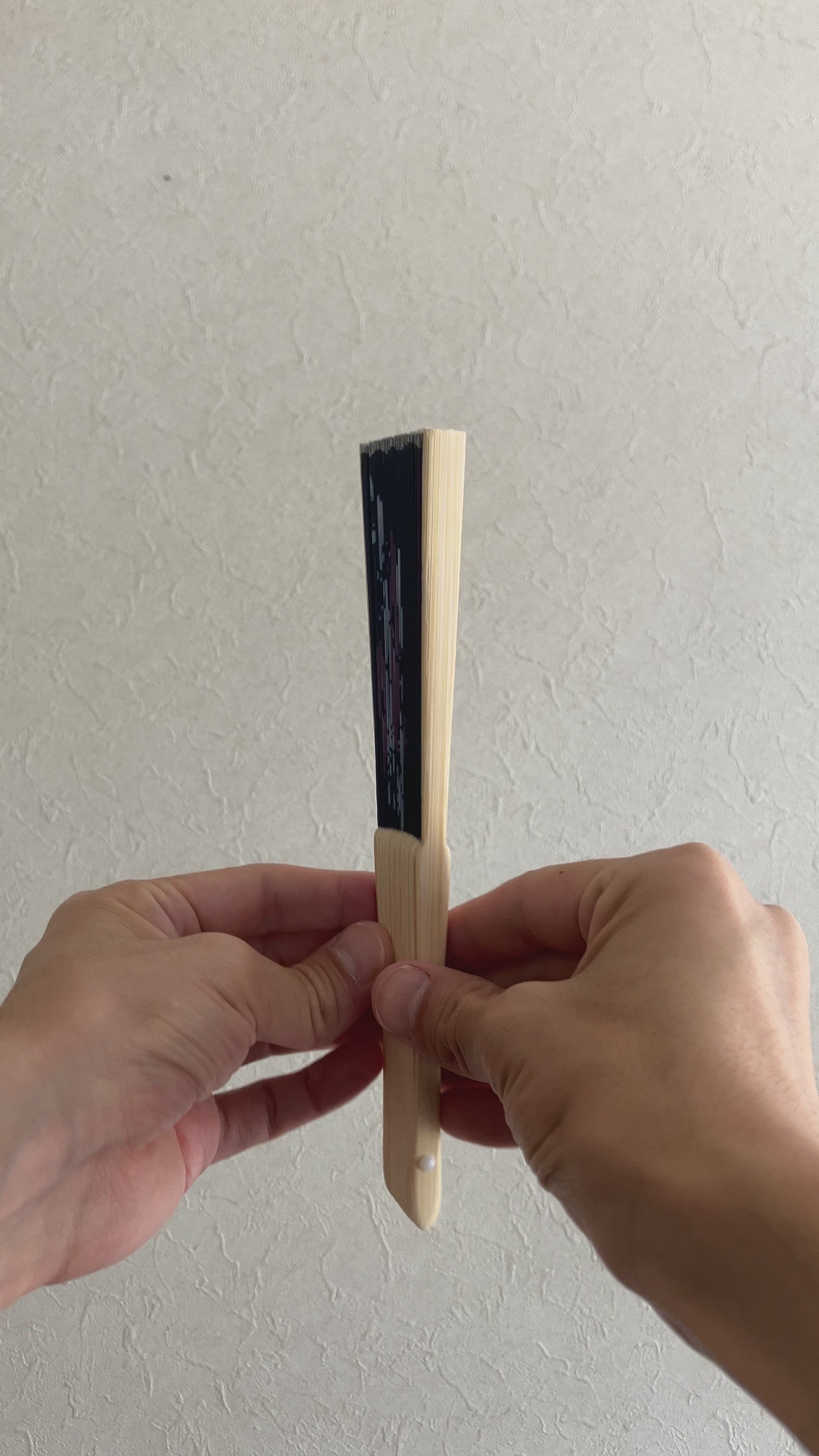Hand slowly unfolds traditional sensu fan with delicate morning glory pattern