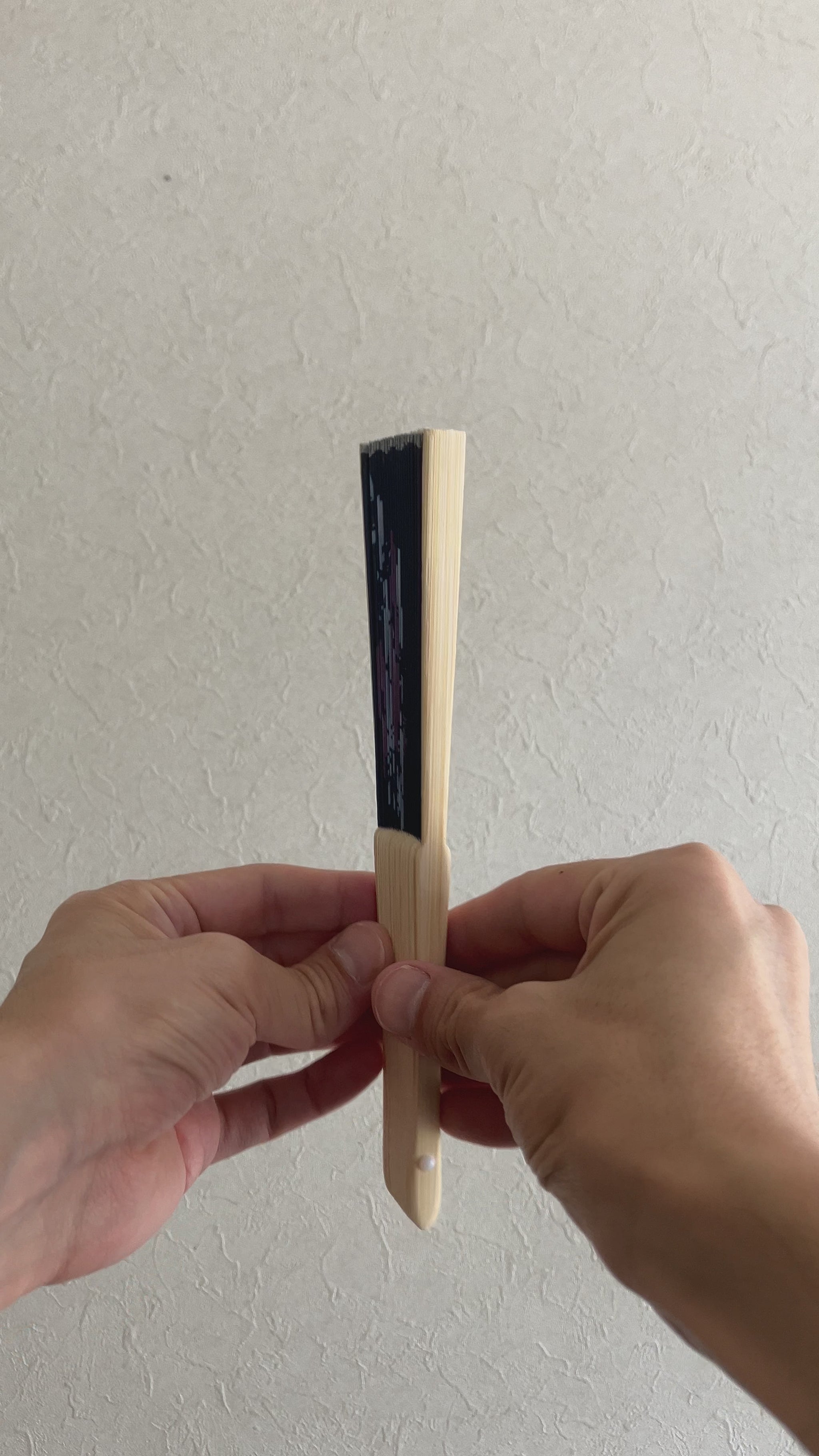 Hand slowly unfolds traditional sensu fan with delicate morning glory pattern
