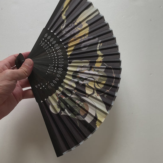Handheld sensu fan creating a gentle breeze outdoors on a sunny day
