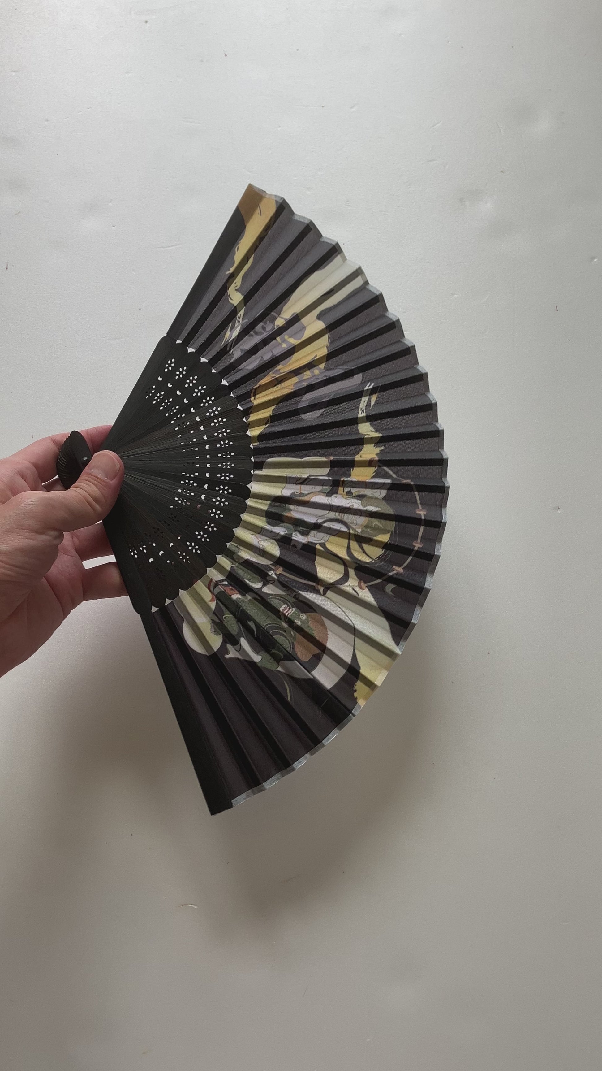 Handheld sensu fan creating a gentle breeze outdoors on a sunny day