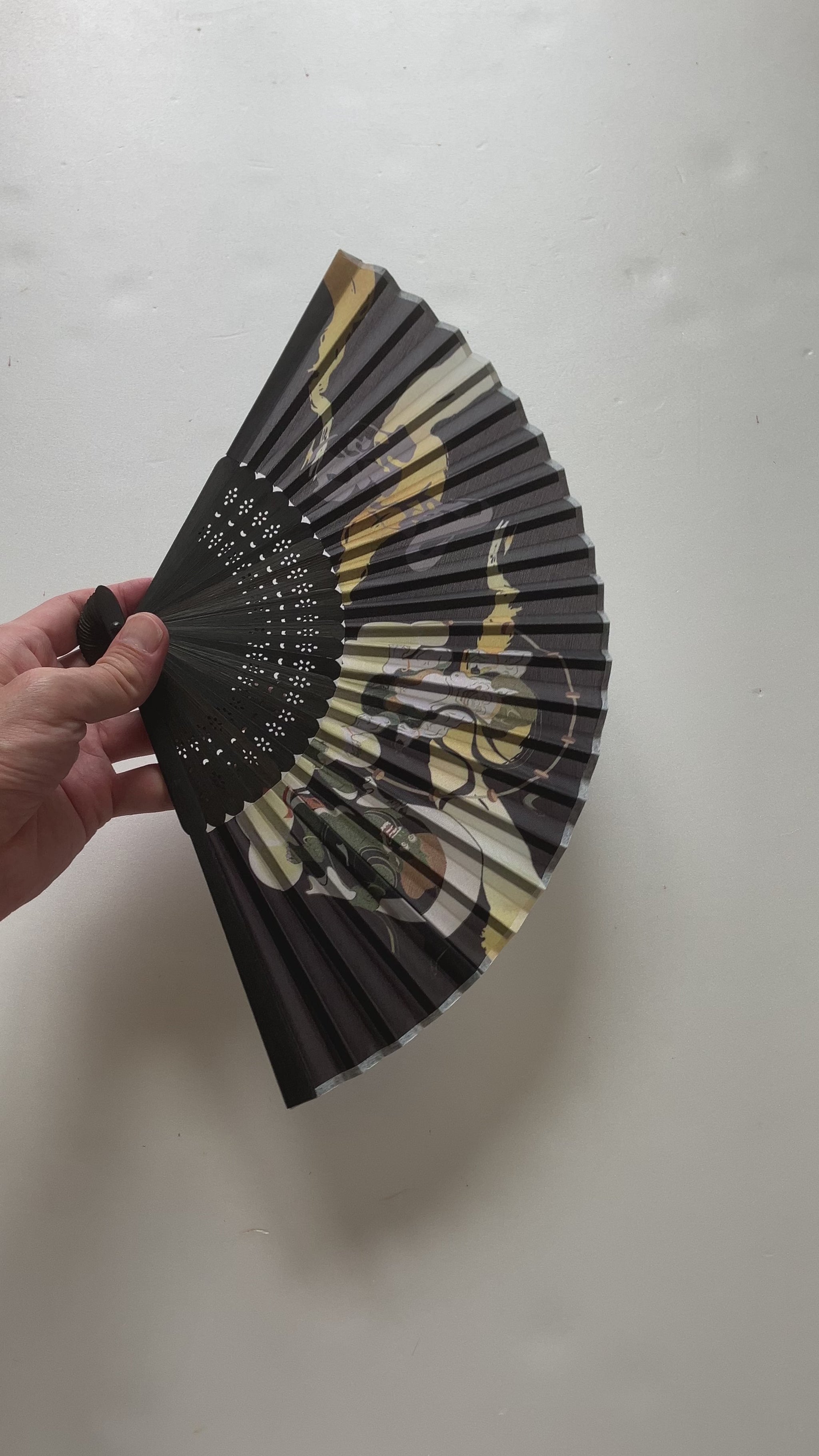 Handheld sensu fan creating a gentle breeze outdoors on a sunny day