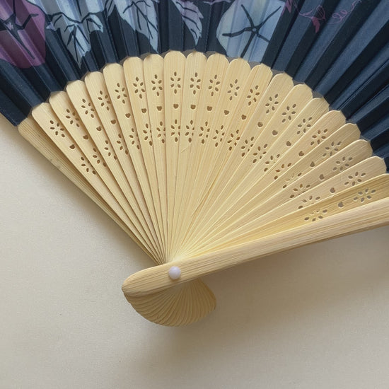 Close-up video of a Japanese folding fan opening to reveal morning glory design