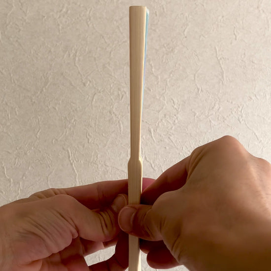 Close-up video of a Japanese folding fan opening to reveal goldfish and demekin design