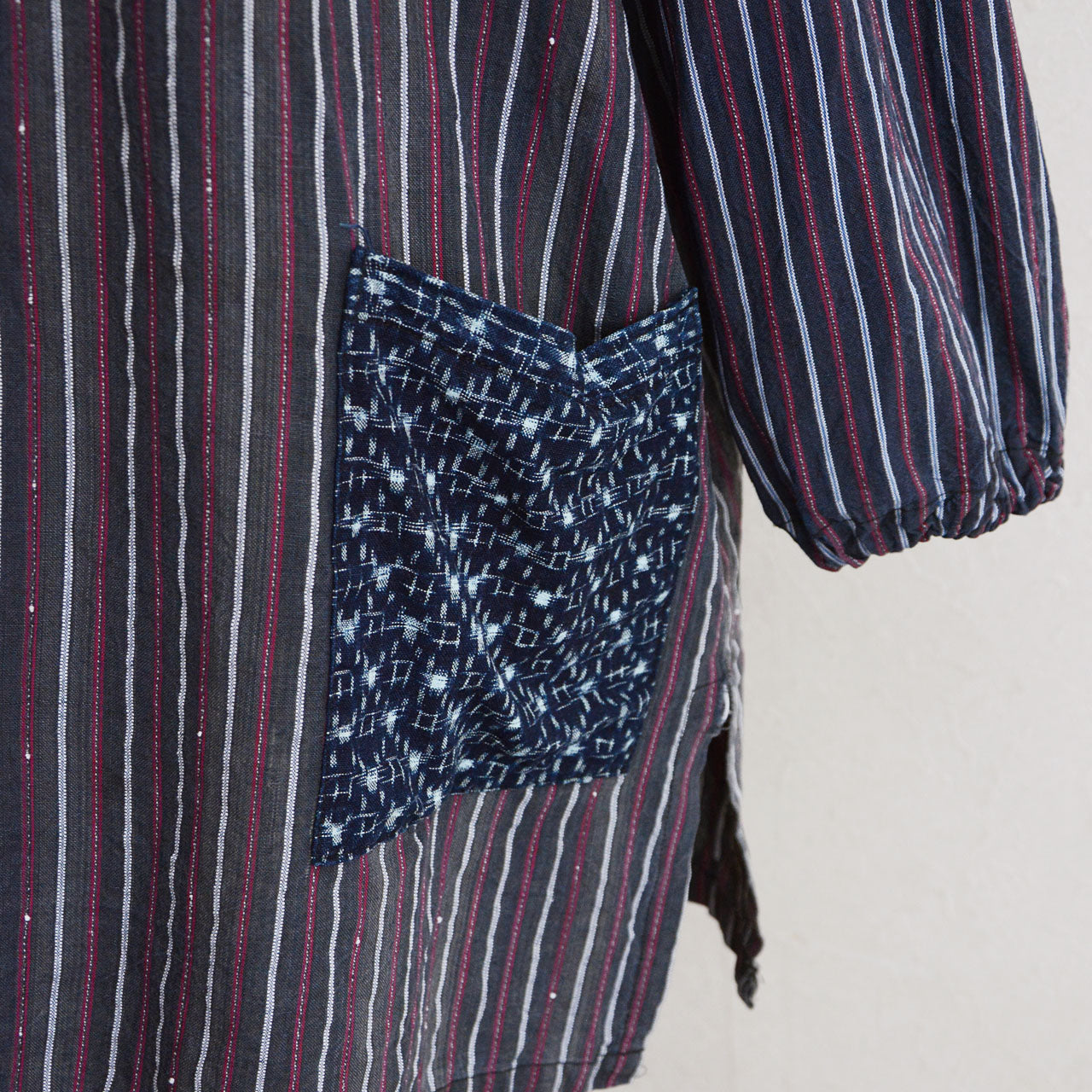 Indigo kasuri pocket close-up on Showa-era stripe cotton tunic, hand-stitched vintage Japanese fabric