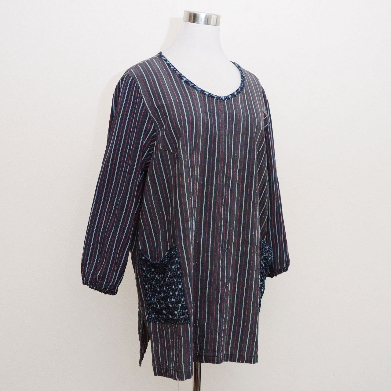 Vintage Japanese remake tunic on dress form, stripe cotton body with indigo kasuri neckline and pockets, side view