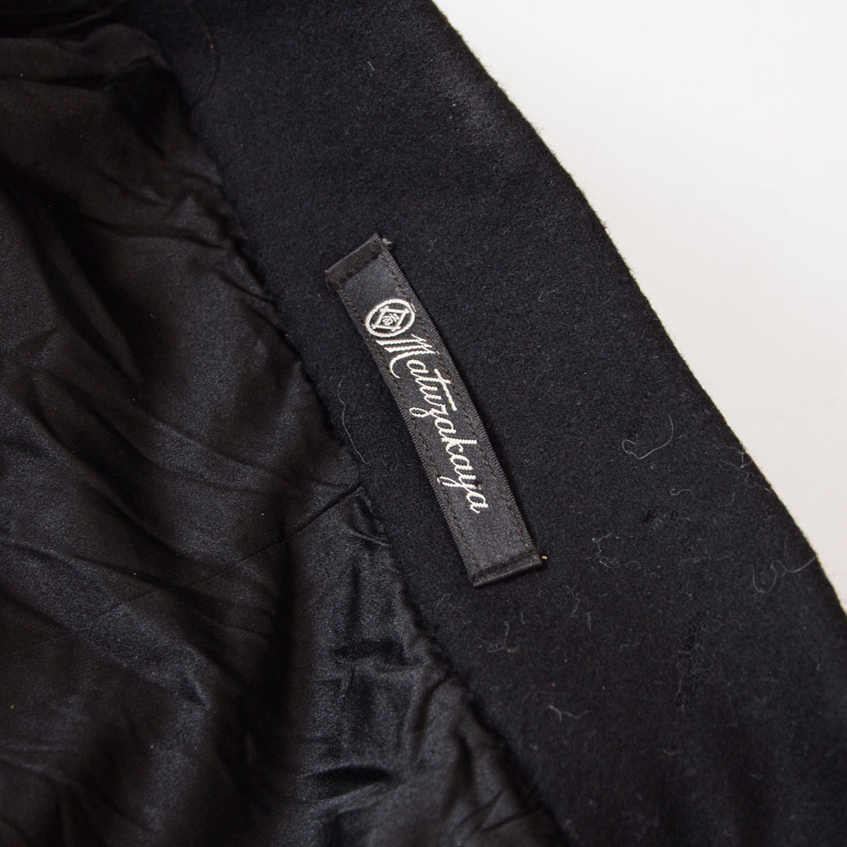 Matsuzakaya label with white script and emblem on a black wool Japanese vintage tonbi coat