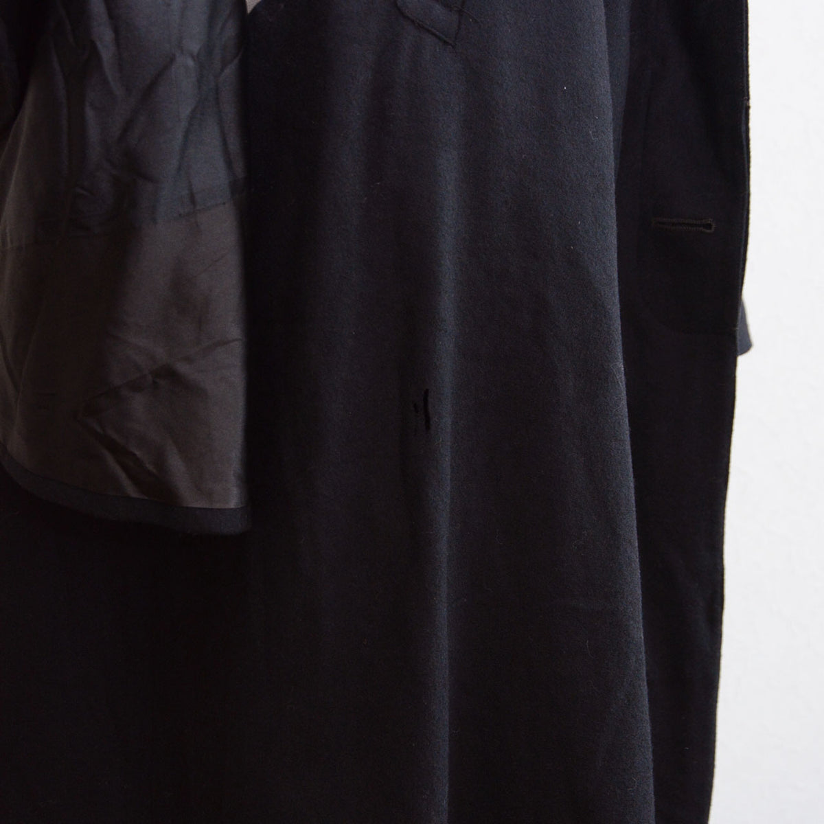 Small hole in the black wool fabric of a Matsuzakaya Japanese vintage tonbi coat
