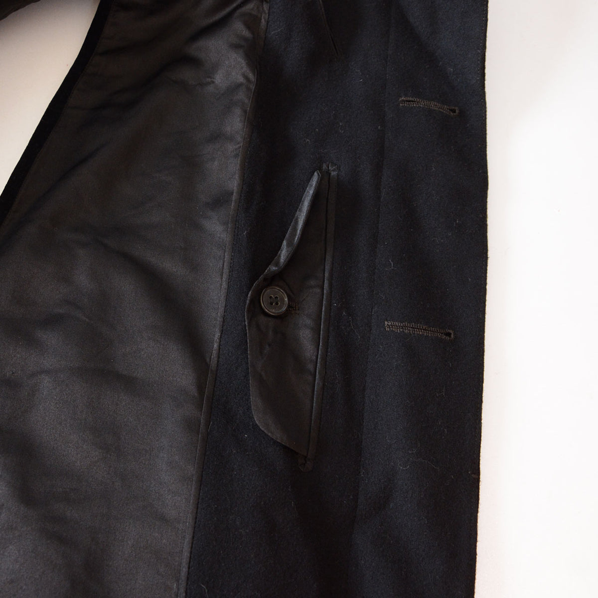 Vertical flap pocket with button and front buttonholes on a Matsuzakaya black wool Japanese vintage tonbi coat