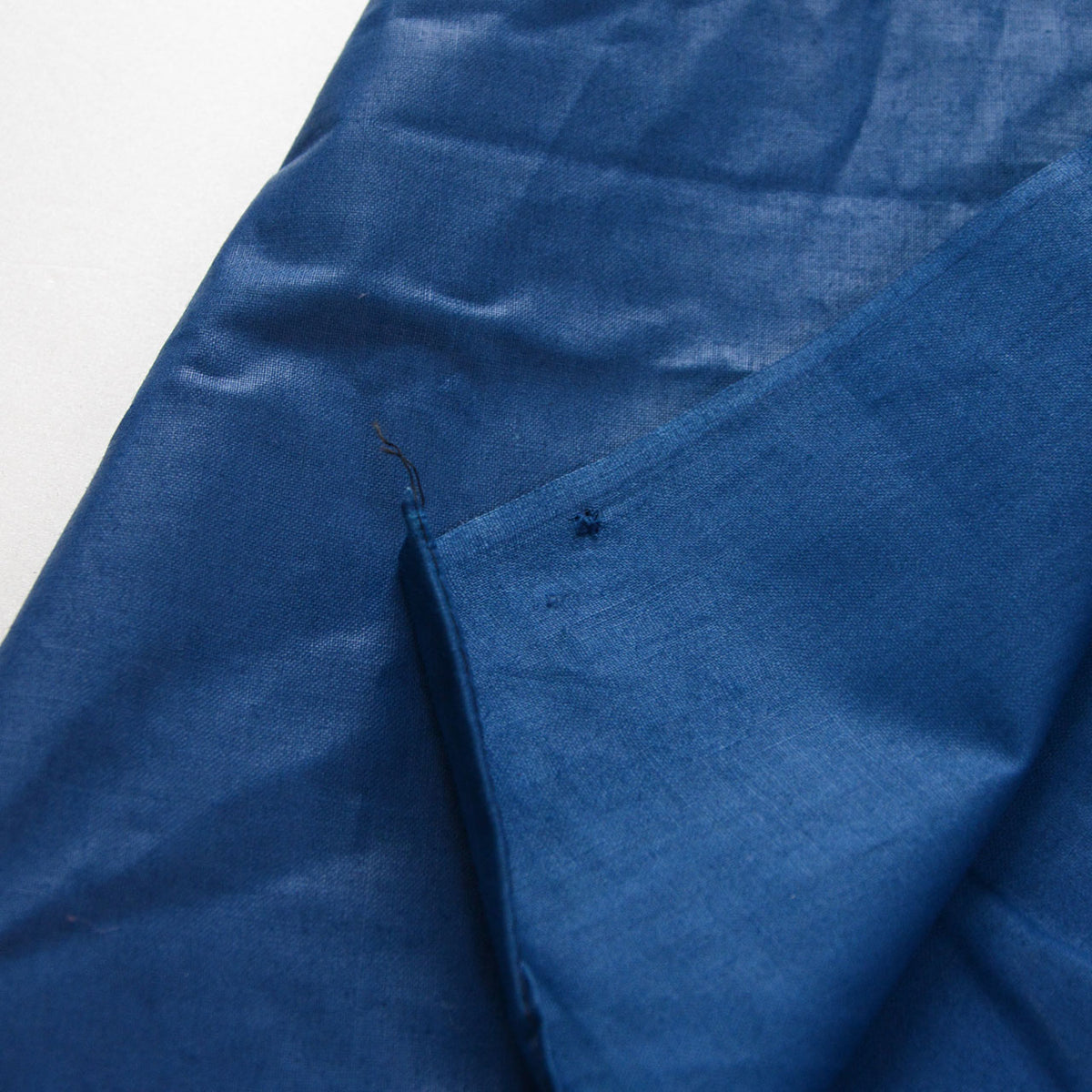 Blue cotton furoshiki with a small hole, loose thread, and faint discoloration