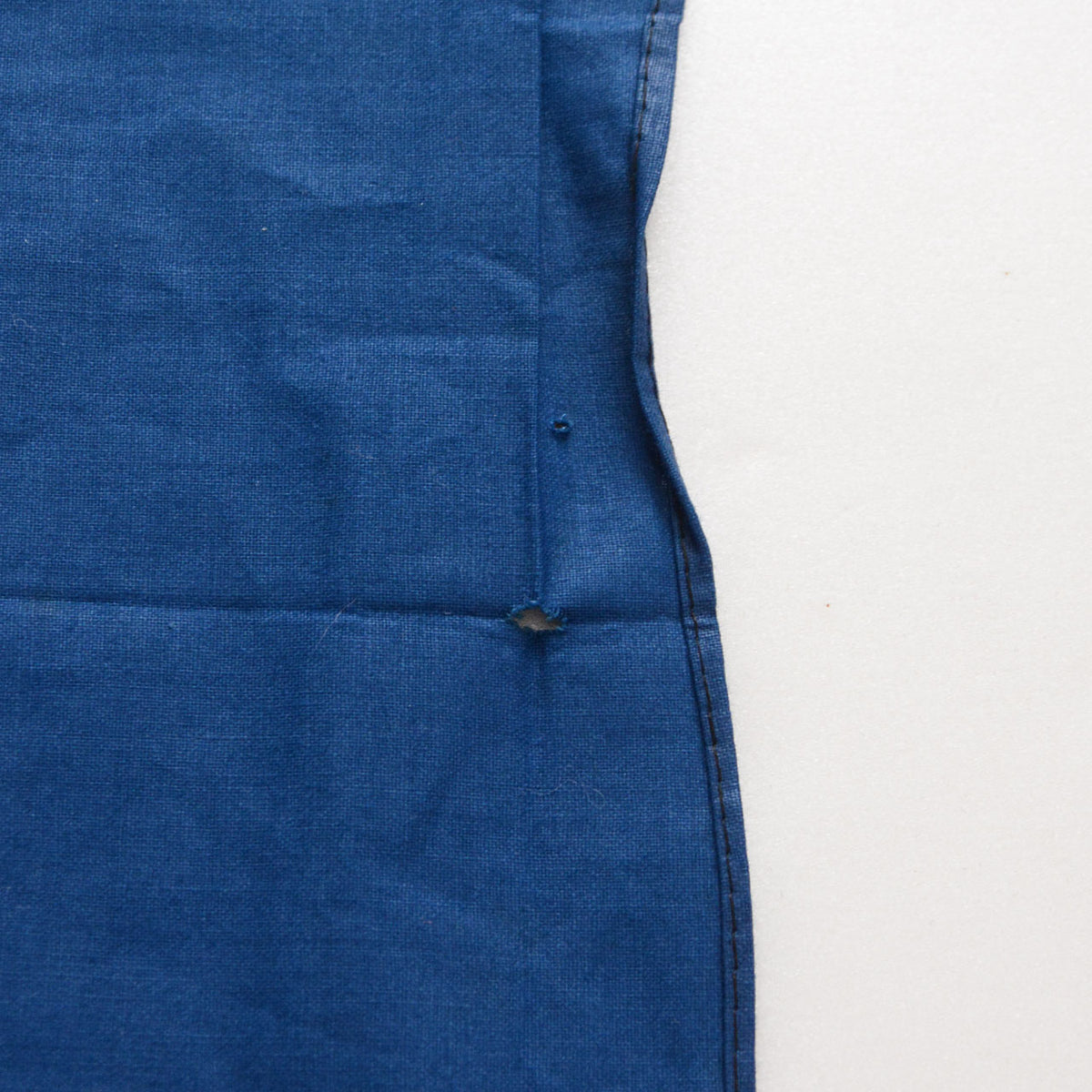 Blue cotton furoshiki with small holes and damaged fabric near the stitched edge