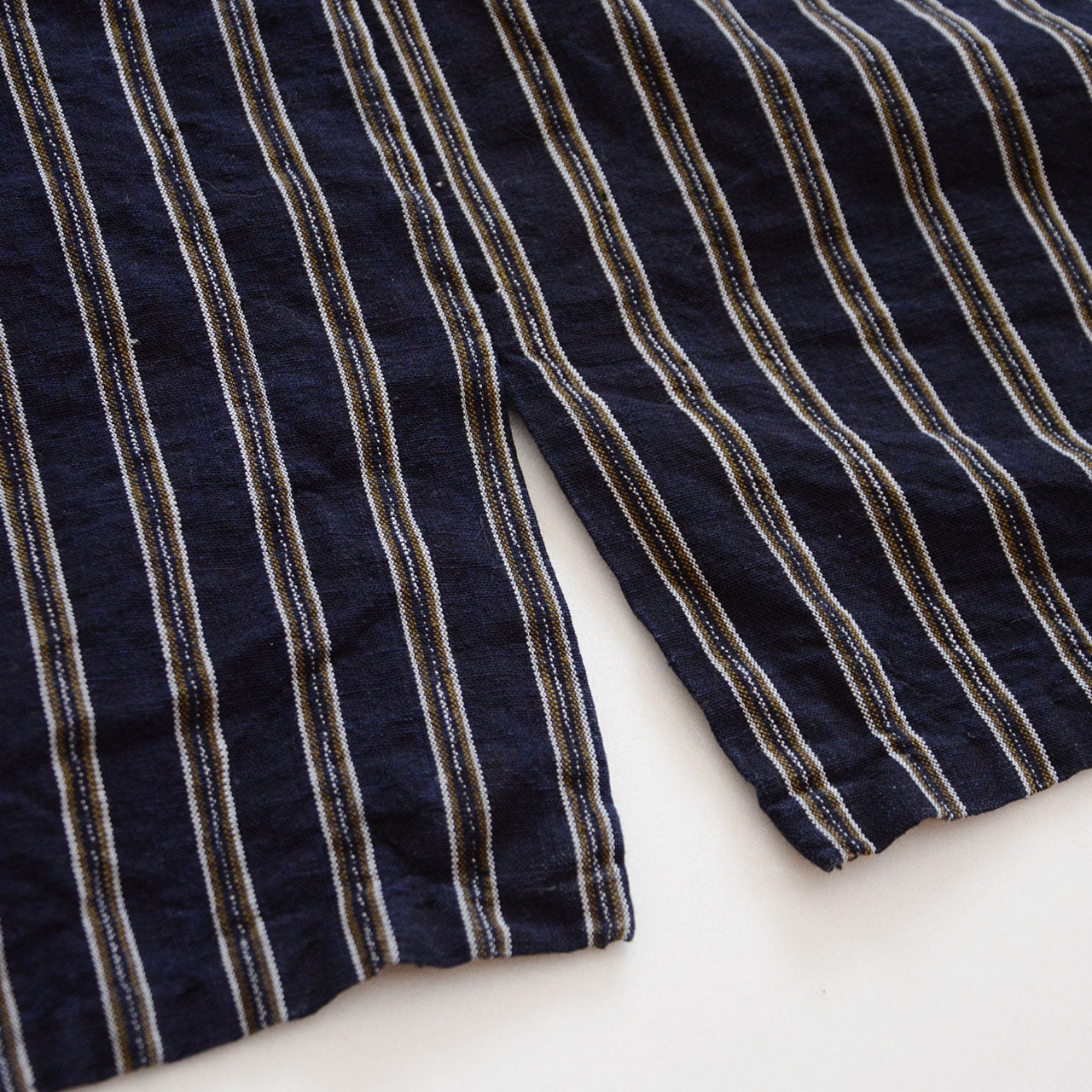 Indigo-dyed collar adding depth and contrast to the striped cotton body.